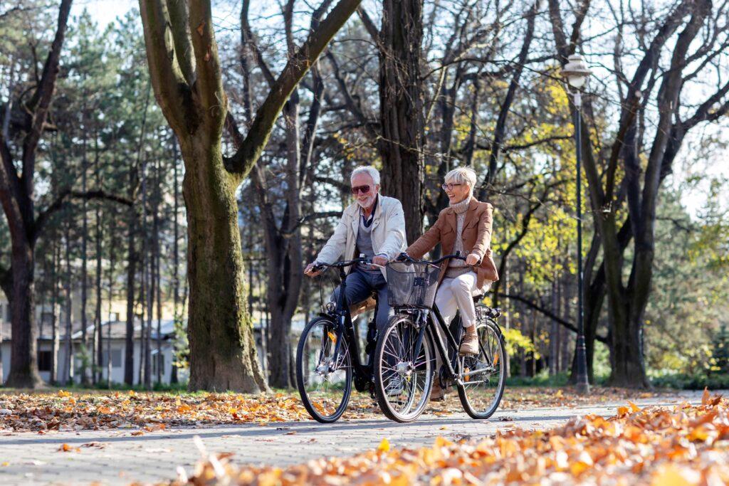 Reifes, fittes Paar fährt mit Fahrrädern durch öffentlichen Park