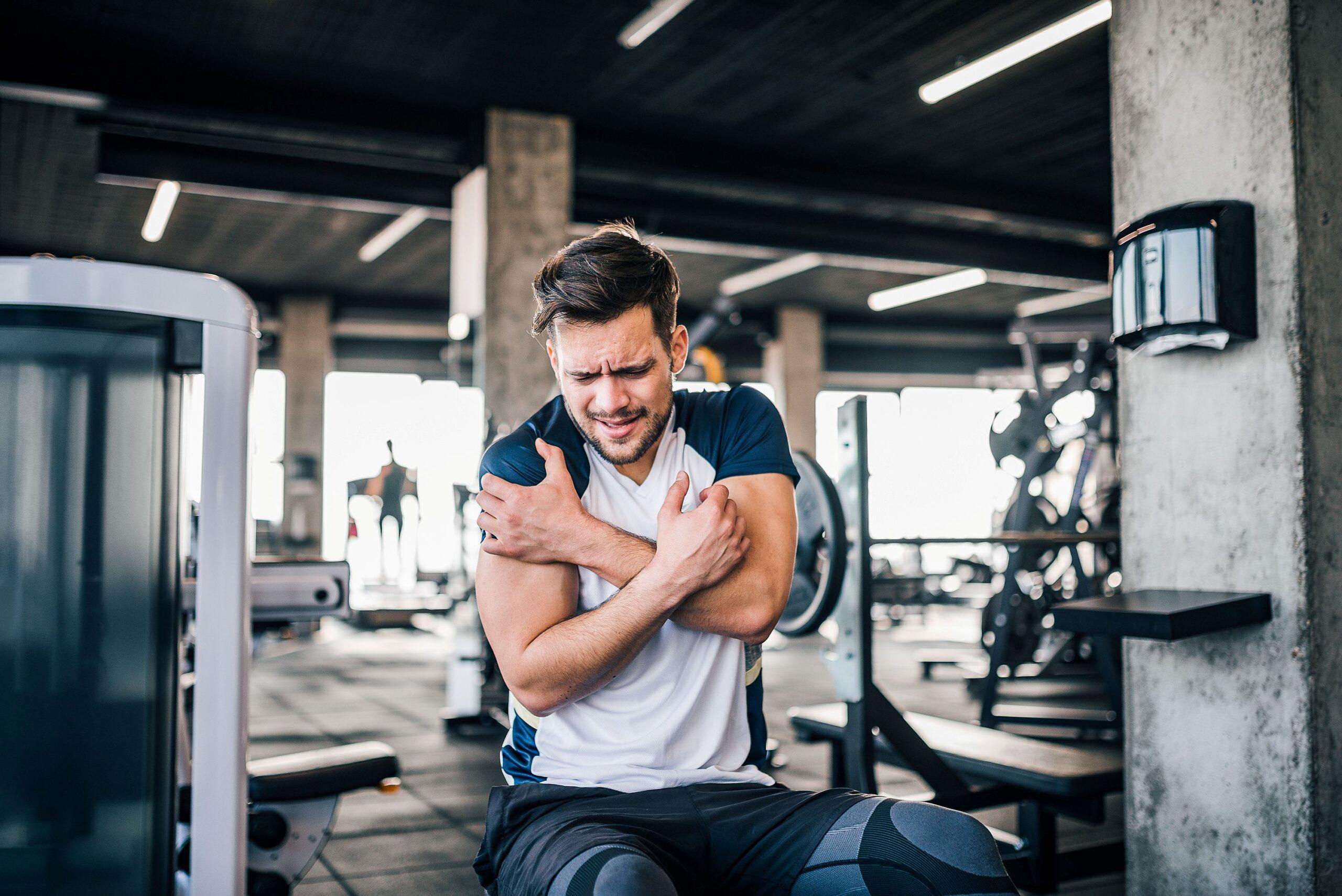 Eine Person befindet sich in einem Fitnessstudio und hält sich den Arm 